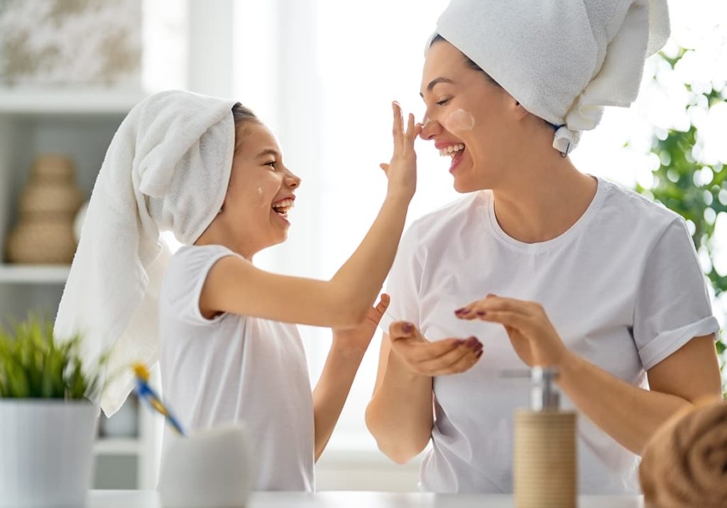 Mère et sa fille se passant de la crème hydratante sur le visage